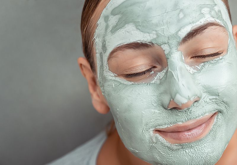 Mujer con una mascarilla facial en color verde.